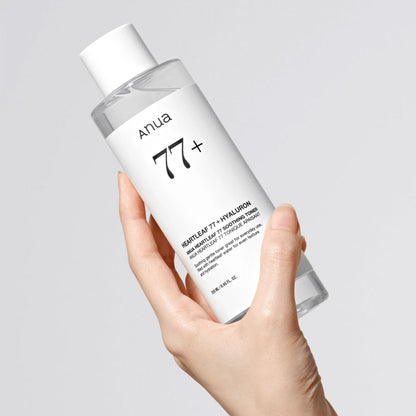 Hand holding a bottle of Anua 77+ skincare product on a light gray background