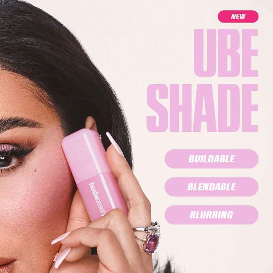 Woman applying makeup with a pink UBE Shade product on a white background